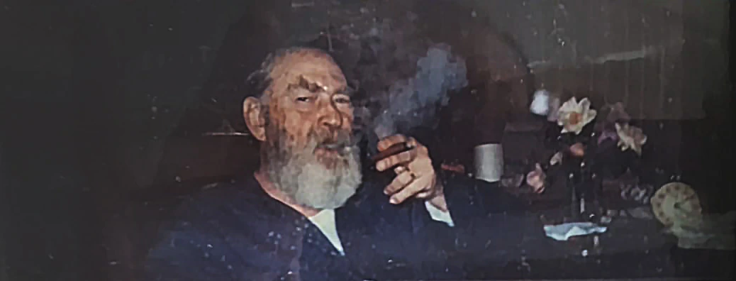 Foto de Maximiliano Henneman em sua casa, fumando um charuto.